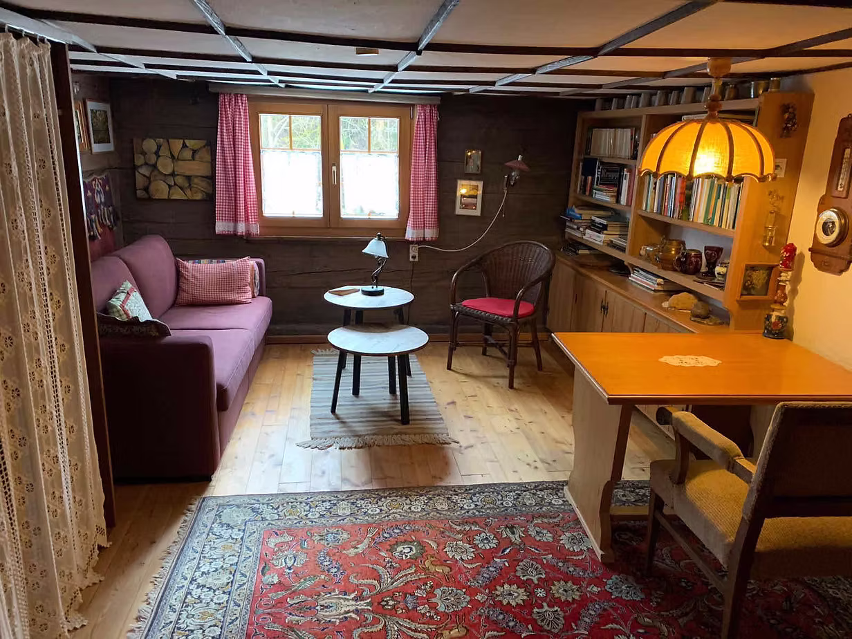 Wohnzimmer mit Sofa, Schreibtisch und Bücherregal