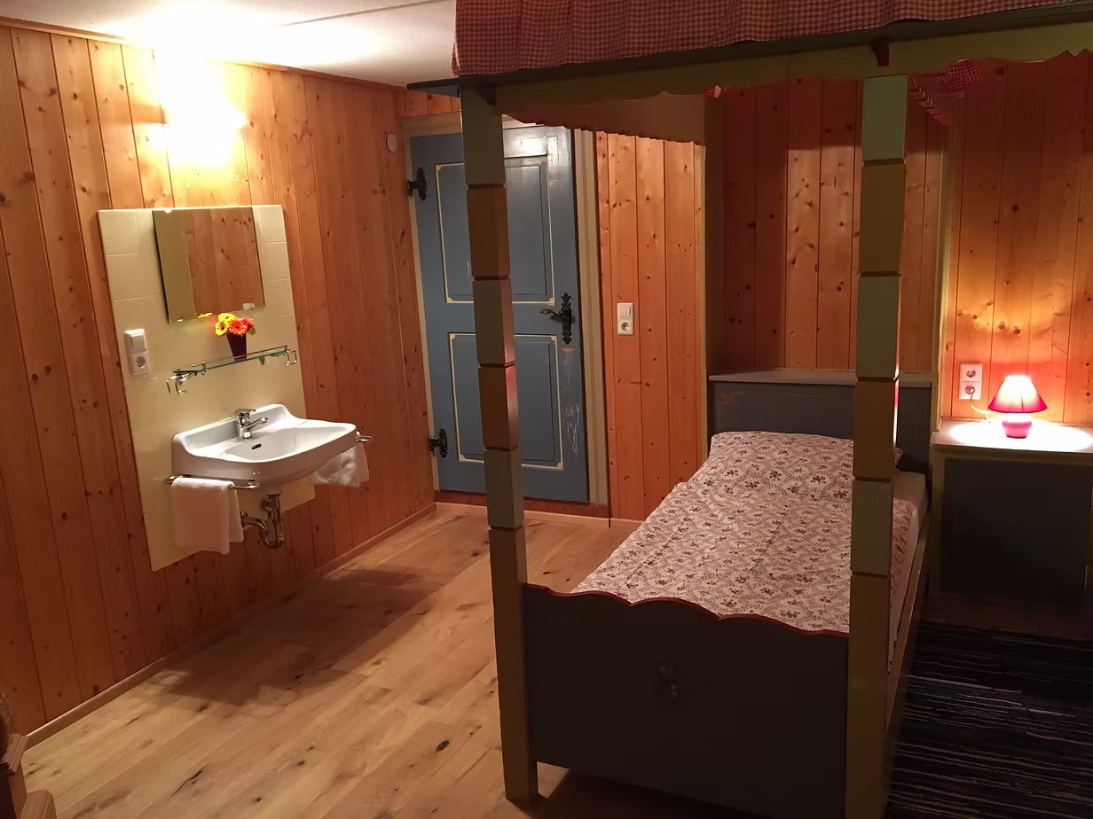 Holzvertäfeltes Zimmer mit antikem Bett und Waschbecken